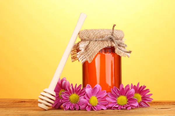 Söt honung i burk med drizzler på träbord på gul bakgrund — Stockfoto