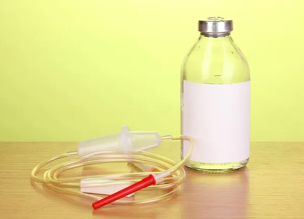 Botella de antibióticos intravenosos y set de infusión de plástico sobre mesa de madera sobre fondo verde — Foto de Stock