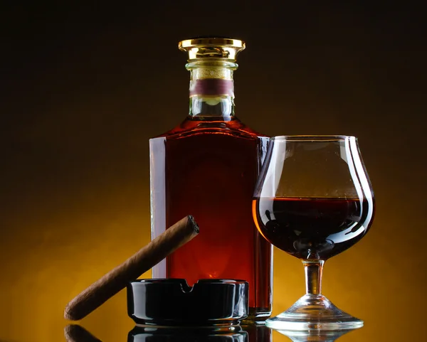 Bottiglia e bicchiere di brandy e sigaro su sfondo marrone — Foto Stock