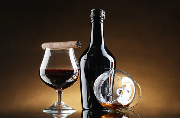 Şişe ve brendi ve puro kahverengi zemin üzerinde glasss — Stok fotoğraf
