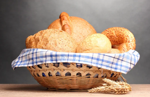 Delicioso pan en cesta y orejas sobre mesa de madera sobre fondo gris —  Fotos de Stock