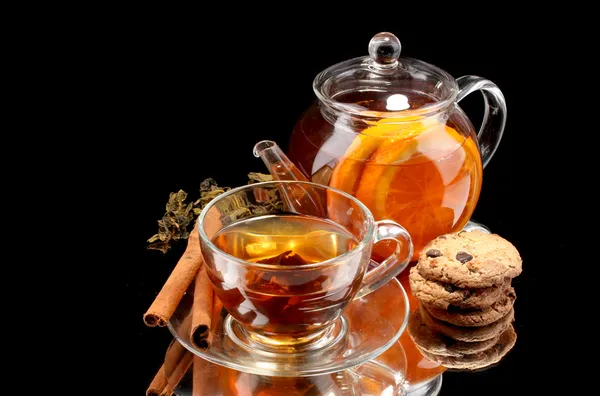 Teiera di vetro e tazza con tè alla frutta nera e biscotti isolati su bianco — Foto Stock