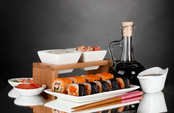 Delicioso sushi en el plato, palillos, salsa de soja, pescado y camarones sobre fondo gris —  Fotos de Stock