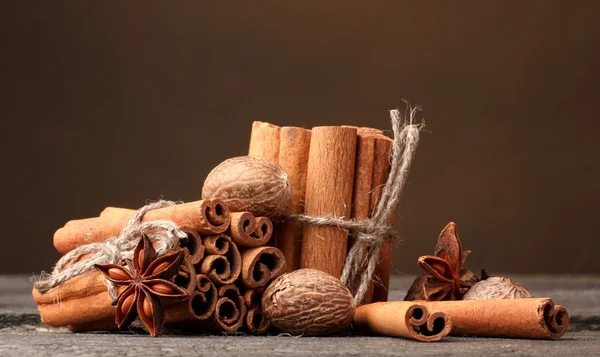Bâtonnets de cannelle, muscade et anis sur table en bois sur fond brun — Photo