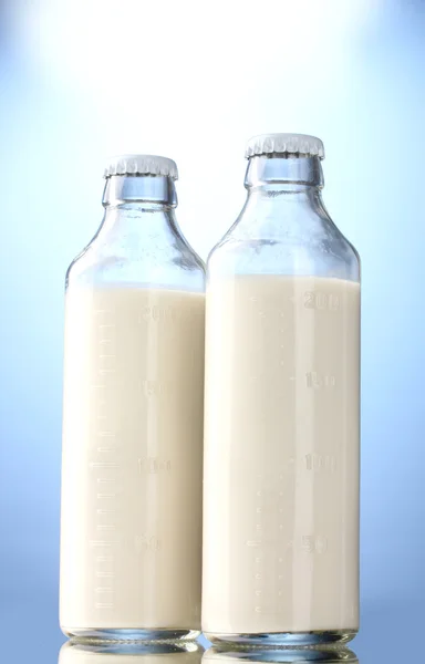 Lahví mléka na modrém pozadí — Stock fotografie