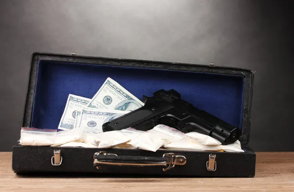 Cocaine, dollars and handgun in case on wooden table on grey background — Stock Photo, Image