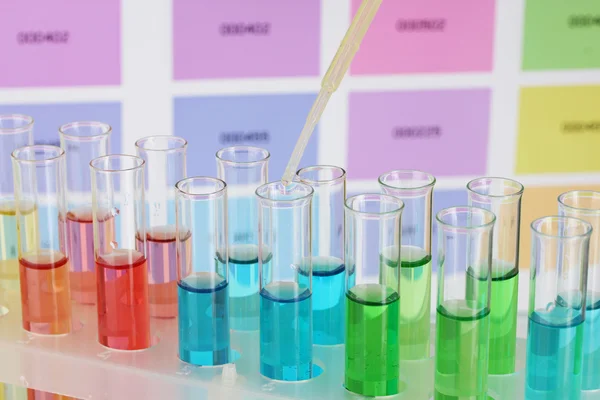 Tubos de ensaio com líquido de cor e pipeta em fundo de amostras de cor — Fotografia de Stock