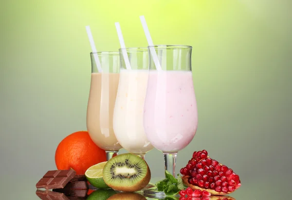 Melk schudt met vruchten en chocolade op groene achtergrond — Stockfoto