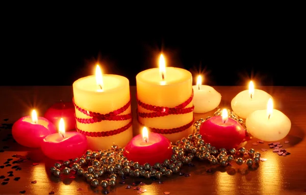 Belle candele e decorazioni su tavolo in legno su sfondo nero — Foto Stock