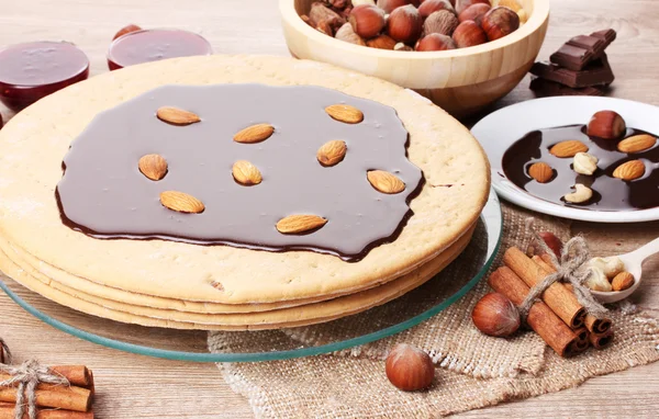 Cake on glass stand and nuts on wooden table — Stock Photo, Image