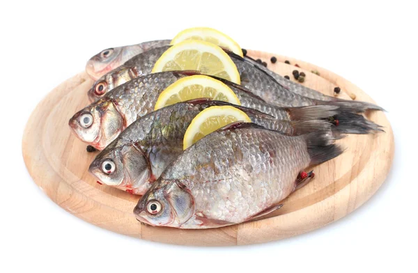 Peixes frescos com limão e especiarias em tábua de corte de madeira isolada em branco — Fotografia de Stock