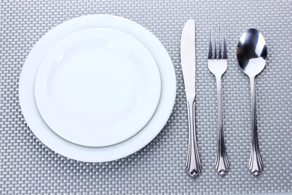 灰色のテーブル クロスにナイフとフォーク、スプーンの白の空の皿 — ストック写真