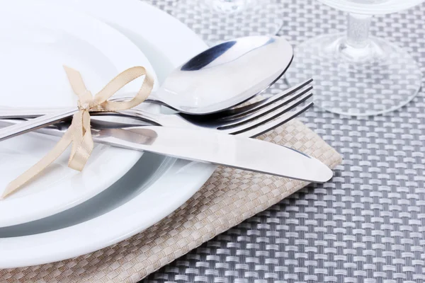 Białe puste talerze, widelec i nóż związany ze wstążki i okulary na szary Obrus — Zdjęcie stockowe