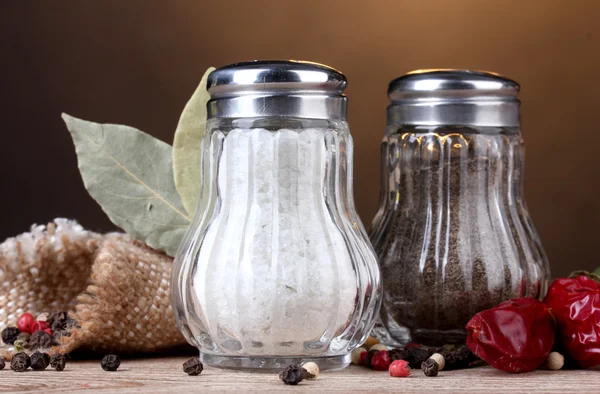 Salt och peppar mal och kryddor på träbord på brun bakgrund — Stockfoto