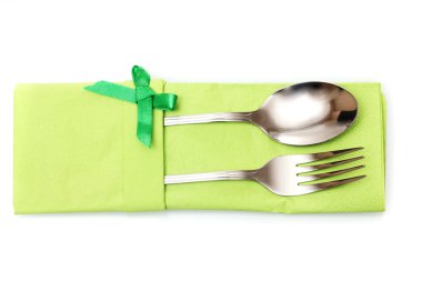 Fork and spoon in a green cloth with a bow isolated on white