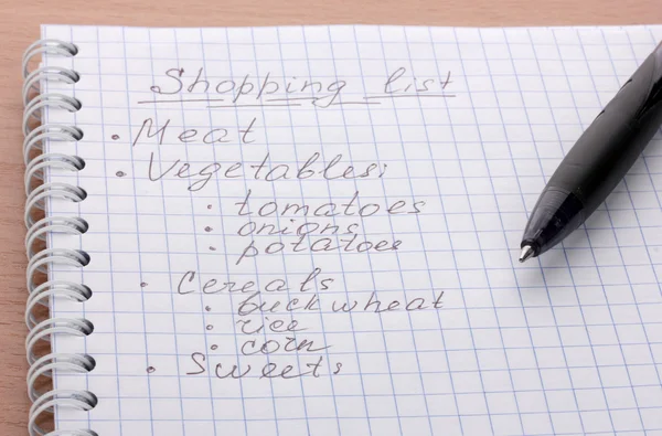 Einkaufsliste und Stift auf Holztisch — Stockfoto