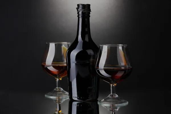 Glas konjak och flaska på grå bakgrund — Stockfoto