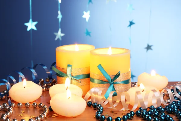 Hermosas velas, regalos y decoración en mesa de madera sobre fondo azul — Foto de Stock