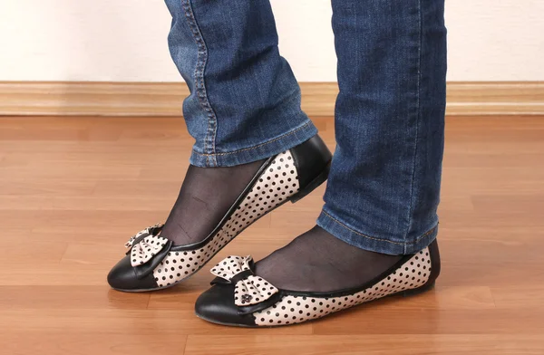 Beine in Jeans und Ballettschuhe auf hölzernem Hintergrund — Stockfoto