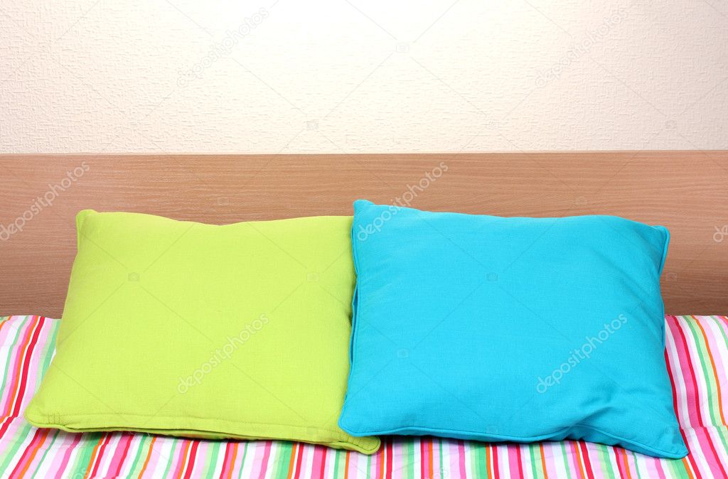 Bright pillows on bed on beige background