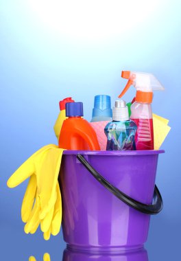 Bucket with cleaning items on blue background clipart