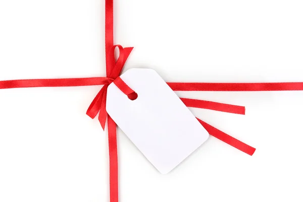 Üres ajándék címke a elszigetelt fehér, piros szatén szalag íj — Stock Fotó