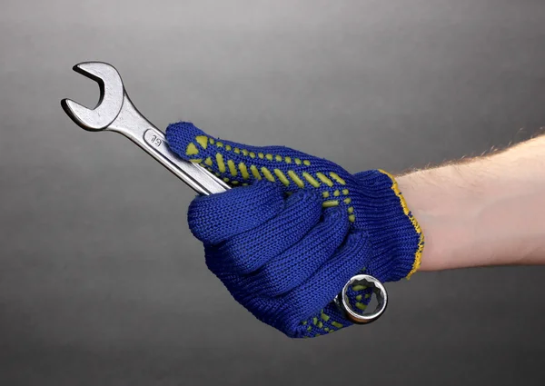 Sleutelmaat in de hand met bescherming handschoen op grijze achtergrond — Stockfoto