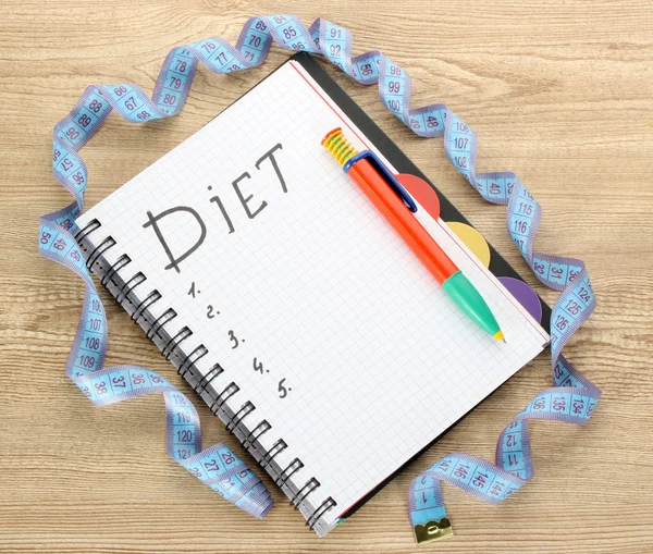 Planowania diety. Notatnik pomiaru taśmę i pióra na drewnianym stole — Zdjęcie stockowe