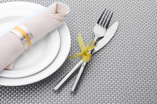 Placi goale albe cu furculiță și cuțit legat cu o panglică pe o față de masă gri — Fotografie, imagine de stoc