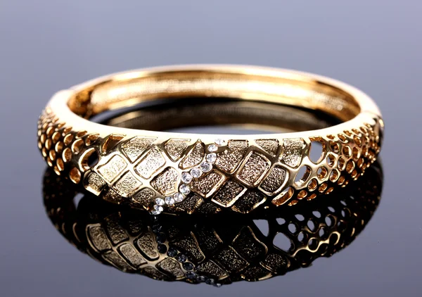 Bellissimo braccialetto d'oro con pietre preziose su sfondo grigio — Foto Stock