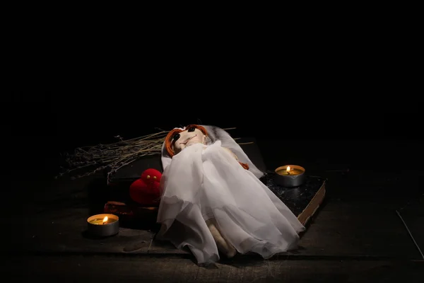 Voodoo boneca menina-noiva em uma mesa de madeira à luz das velas — Fotografia de Stock