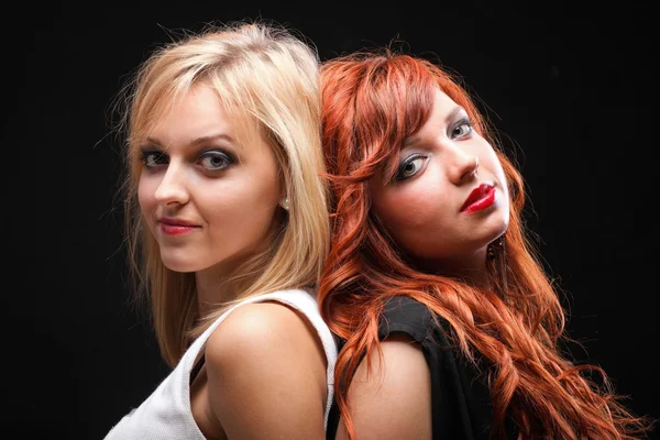 Two happy young girlfriends black background — Stock fotografie
