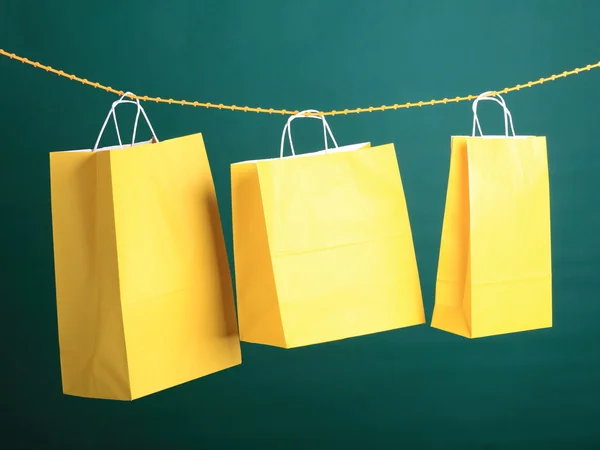 购物在绿色背景上的黄色礼品袋 — 图库照片