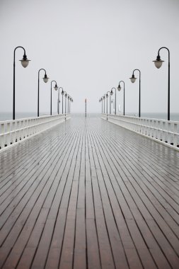 Old pier in rain on Baltic sea Orlowo Gdynia Poland clipart