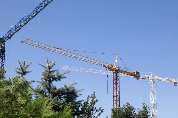 Construction cranes silhouetted against blue sky — Stock Photo, Image