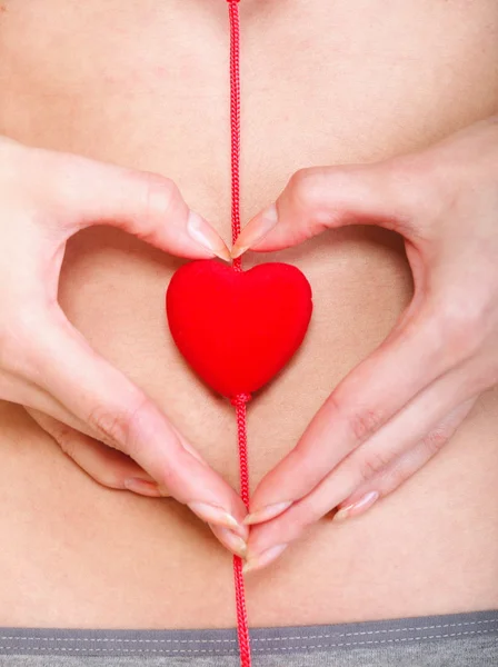 stock image Sexy young woman red heart shape hands belly