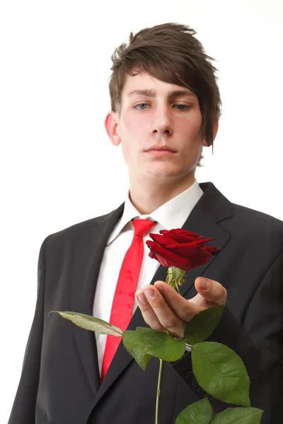 Jovem apresentando uma flor vermelha rosa isolada — Fotografia de Stock