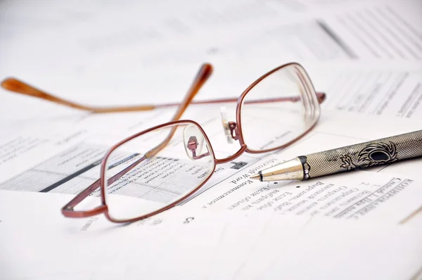 Brille und Bleistift auf einem Dokument Stockbild