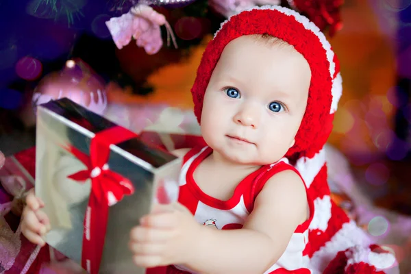 Χαριτωμένο μικρό κορίτσι σε ένα κόκκινο καπάκι με ένα νέο έτος δώρο — Φωτογραφία Αρχείου