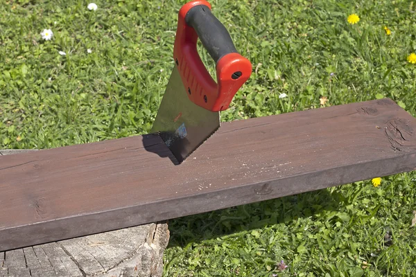 The saw and the wooden board — Stock Photo, Image
