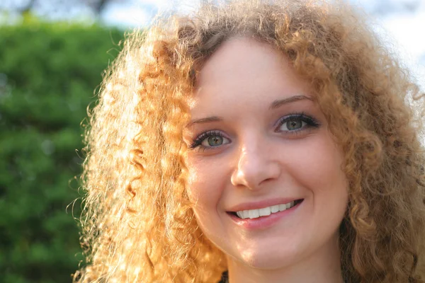 Curly-haired meisje glimlachend in het voorjaar — Stockfoto