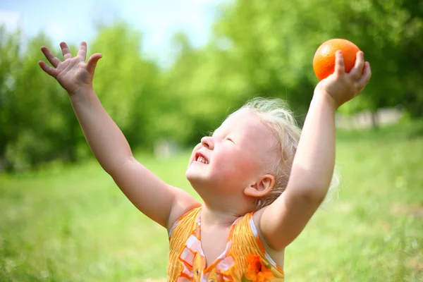 Child plays with orange — Stock Photo, Image