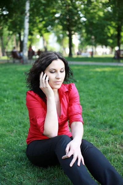 Девушка с телефоном сидит на траве — стоковое фото