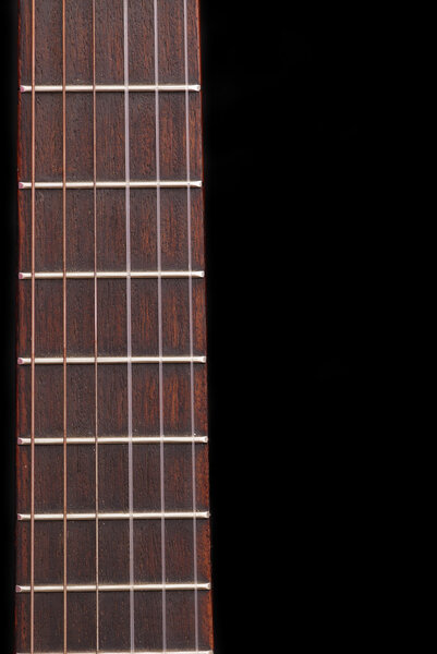 Detail of classic guitar (Spanish) fretboard, against black background.