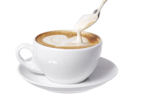 Hjärtat dras in i latte med sked. Stockbild