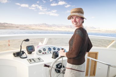 Attractive young woman steering a boat clipart