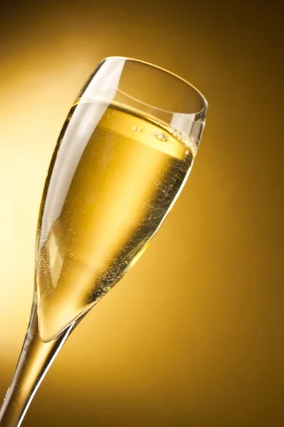Uma flauta de champanhe contra um fundo dourado — Fotografia de Stock