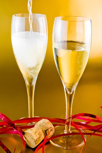A pair of champagne flutes with decoration on golden background — Stock Photo, Image