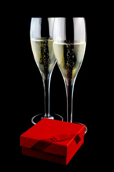 Due bicchieri con champagne vicino a un regalo — Foto Stock