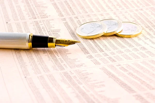 Moedas em euros e uma caneta dourada no jornal financeiro — Fotografia de Stock